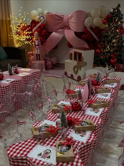 A full view of the Christmas party, with a long, beautifully decorated kids' dining table set against the backdrop of the glowing Christmas tree and balloon arch.