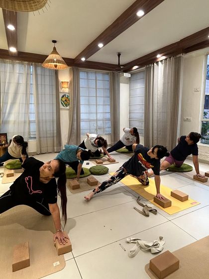 Students in a side plank variation, using yoga blocks for hand support. This modification helps maintain alignment and stability while building oblique strength.
