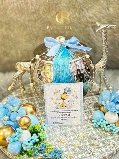 A unique and luxurious baby announcement hamper. This one features a silver-plated, camel-shaped container on a decorated tray, with a personalized card announcing the baby's arrival.
