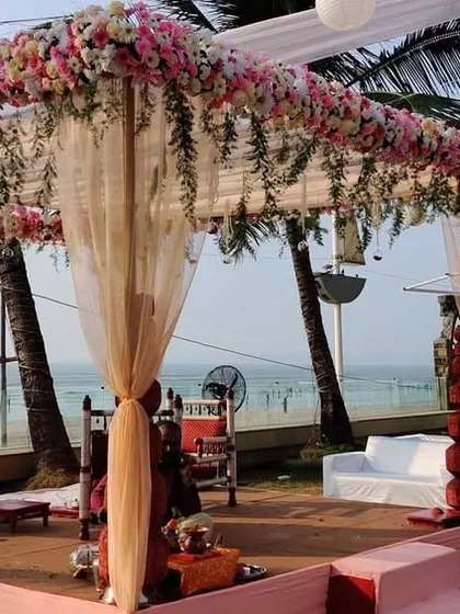 A side view of a floral mandap setup for a beach wedding. The design features traditional stacked pots on the pillars, adding a classic touch to the modern pastel color scheme.