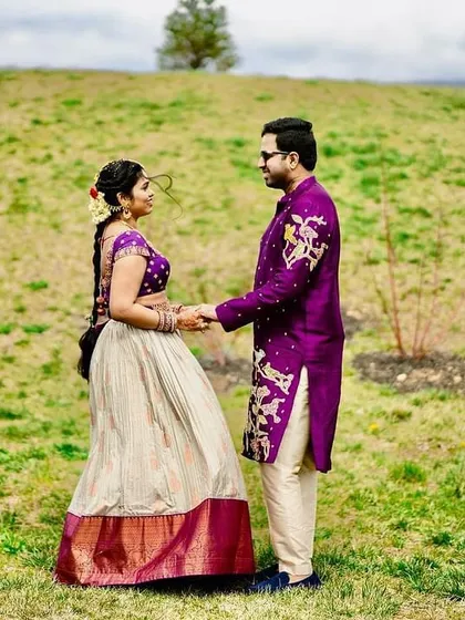 It brings me immense joy to see our creations become a part of your special moments. This beautiful couple radiates happiness in their coordinated bespoke ensembles, a perfect fusion of my signature purple and classic ivory.