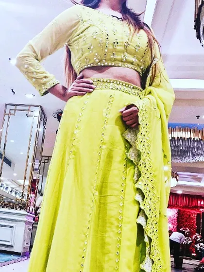 A customer wearing the lime yellow georgette lehenga at an event. This shows how the lightweight fabric and mirror work catch the light, making it a great choice for an evening party or sangeet.