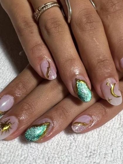 A celestial-inspired set with a trendy twist. These nails feature a soft, milky base, green cat-eye polish, and gold chrome accents in the shape of suns and moons.