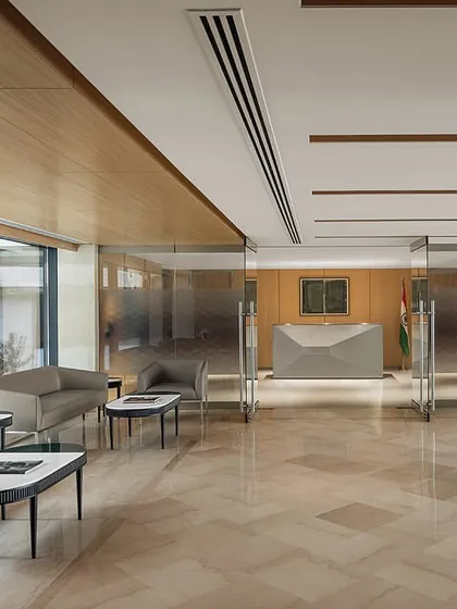 The main reception lounge of The Layered Office, featuring polished marble floors and wood-paneled walls, looks out onto the central courtyard with its grand sculptures.