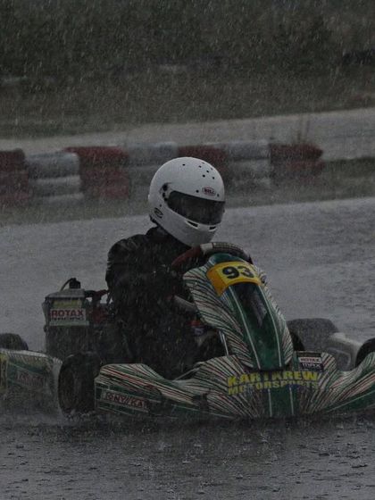 A driver powers through the rain, creating a huge spray.