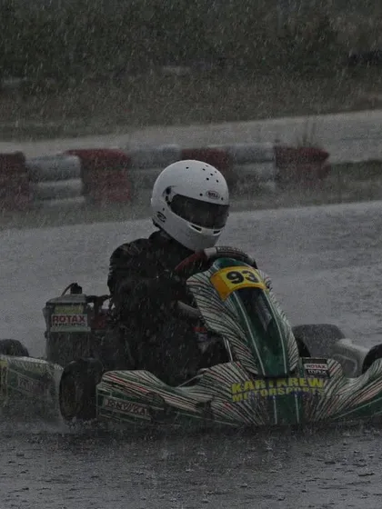 A driver powers through the rain, creating a huge spray.