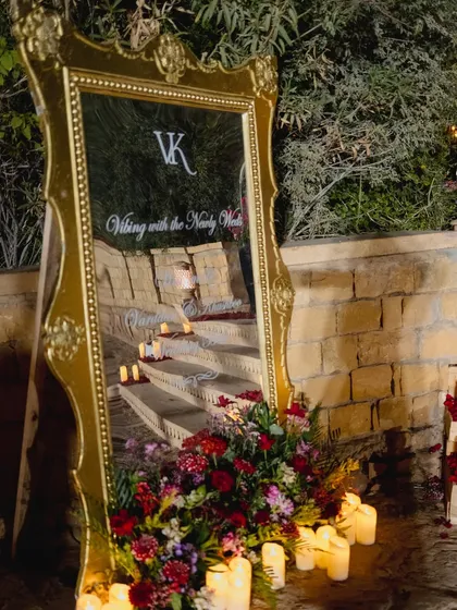 A personalized welcome mirror with an ornate gold frame, reflecting the candle-lit steps and setting a tone of regal romance for the evening reception.