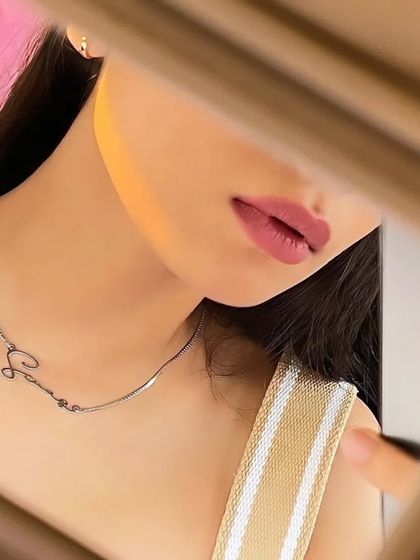 An artfully framed shot of a silver-toned script necklace. This view emphasizes the sleek, snake chain and the fluid design of the custom nameplate.