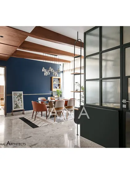 The dining space in Apartment 704 is defined by a bold blue feature wall and antique wooden ceiling beams. This creates a vibrant, playful atmosphere for hosting, in contrast to the more minimal living area.