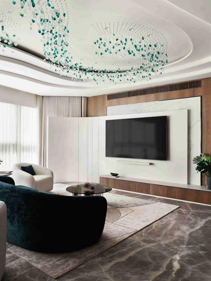 Another view of the living area, highlighting the custom ceiling light fixture and the elegant combination of marble, wood, and plush fabrics.