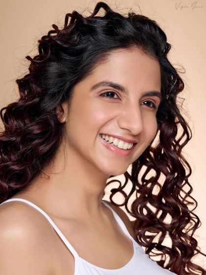 A joyful and energetic beauty shot. The genuine laugh and dynamic hair create a portrait that feels alive and full of personality.