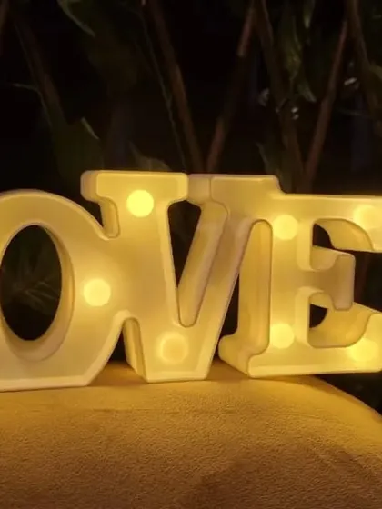 A close-up of the 'LOVE' marquee letters, a popular add-on for anniversaries, proposals, and romantic date nights. The warm light adds a beautiful glow to the room.