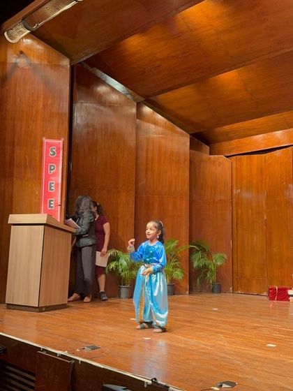 Dressed as a princess, a young performer captivates the audience with her expressive storytelling.