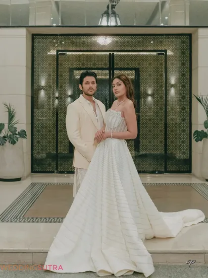 A grand and elegant portrait of the couple at the entrance of a luxury venue. This shot combines architectural beauty with the couple's sophisticated style for a truly regal pre-wedding photo.