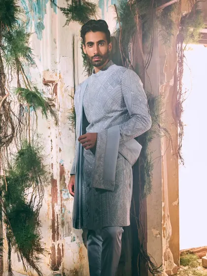 This ensemble in a serene shade of blue redefines modern festive wear. The intricate geometric embroidery and layered silhouette offer a sophisticated alternative for the contemporary groom or guest.