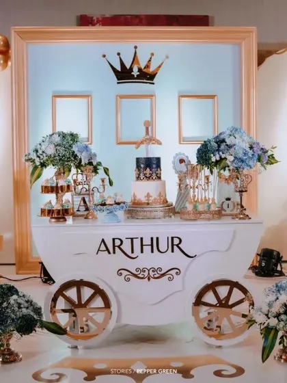 A royal celebration fit for a little prince. This custom-designed dessert carriage, complete with a castle backdrop and a regal blue and gold color scheme, serves as the stunning centerpiece for a memorable first birthday party.