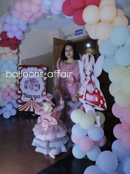 The birthday girl and her mother posing with a character cutout at their pastel-themed party.