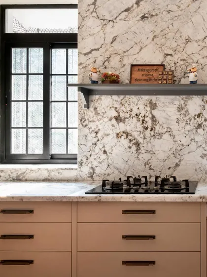Another view of the calm, muted kitchen, showing the beautiful marble-patterned quartz that flows up the wall as a backsplash. The open shelf adds a practical and decorative touch.