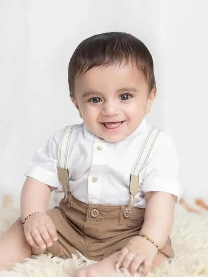 A big, happy smile from this seven-month-old. The classic outfit and simple background make this a perfect milestone photo.