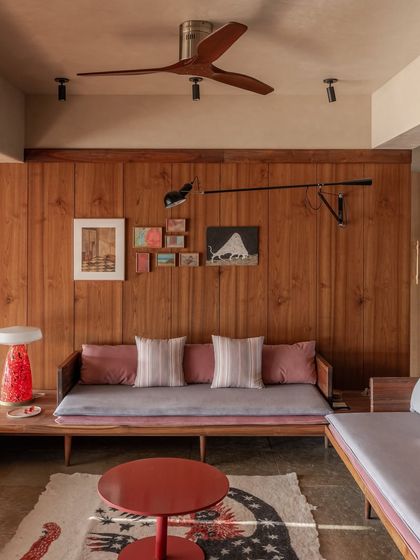 The living room features a floating U-shaped seating arrangement that extends from the raised deck. The continuous use of teak wood on vertical surfaces helps dissolve boundaries and makes the entire space feel more expansive.