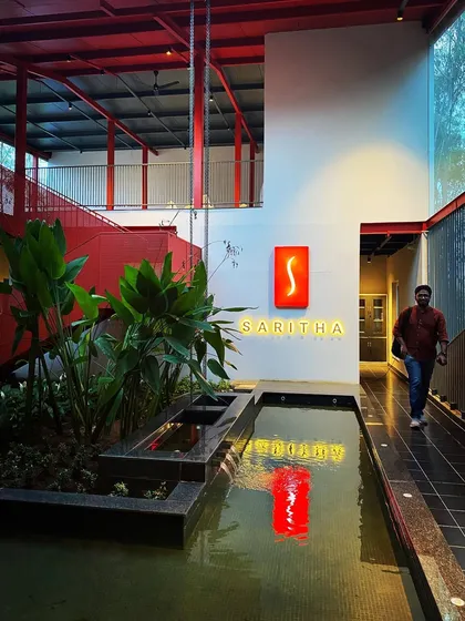An evening view of the SARITHA SERENE office, where the illuminated signage and its reflection in the water create a dramatic effect. This demonstrates our approach to integrating lighting as a key component of architectural identity.