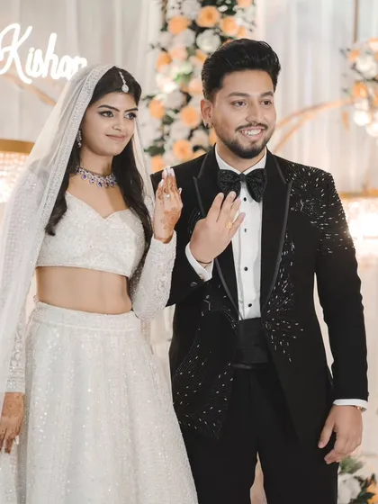 The couple proudly shows off their engagement rings. Their happy smiles and the beautiful floral backdrop capture the joy of the moment.