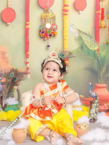 Another angle of our little Krishna, showing the full, vibrant set design with hanging bells and peacocks.