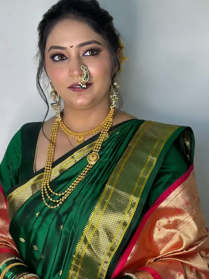 A classic portrait of the bride in her green Paithani saree, showcasing the flawless base makeup and soft contouring.