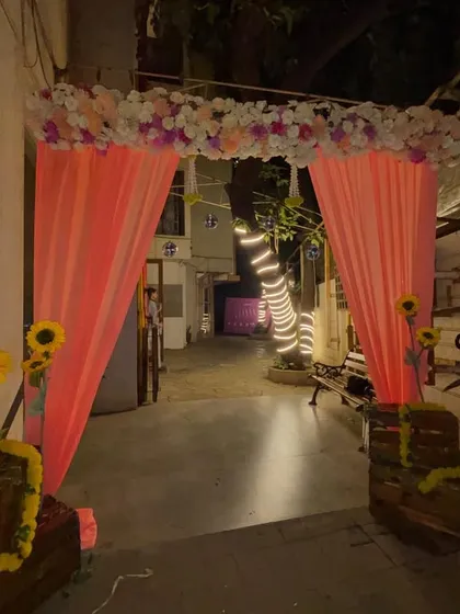 The entrance decor for an engagement party. We created a welcoming arch with pink drapes and a thick floral border, with trees in the background wrapped in fairy lights to extend the magical feel.