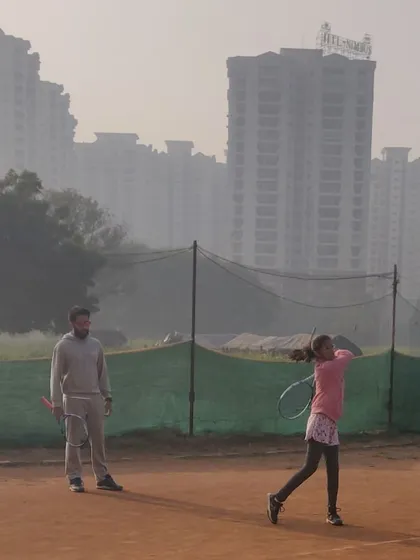 A young player executes a powerful follow-through during a coaching session. We train our juniors on both clay and hard courts to ensure they develop into versatile and adaptable players.