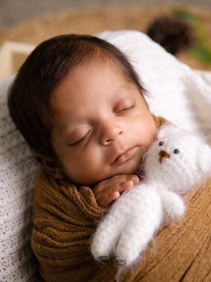 A close-up shot showing the baby cuddling a tiny teddy bear. Adding small props like this can make a portrait even more heartwarming.