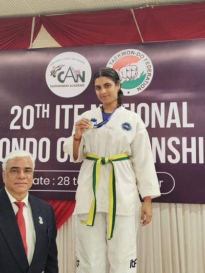 A yellow-green belt student with her silver medal, showing that dedication brings results at every stage of the journey.