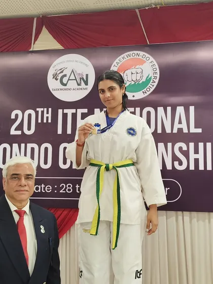 A yellow-green belt student with her silver medal, showing that dedication brings results at every stage of the journey.