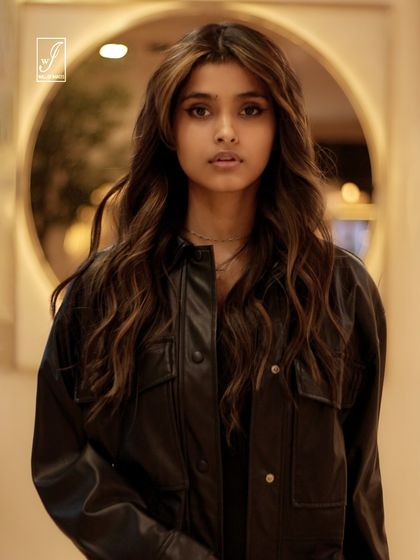 A direct and engaging portrait, framed by a circular light element in the background, which adds depth and visual interest.