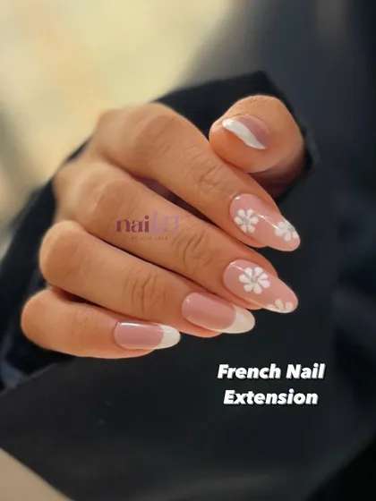 Beauty at your fingertips. A classic French manicure on elegant almond extensions, with two accent nails featuring delicate, hand-painted white daisies.