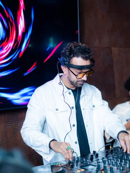 A DJ at the decks, dressed in white to match the party's theme. We ensure every detail, including our artists' attire, aligns with the event concept.