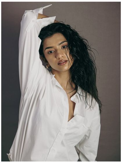 A classic beauty pose that elegantly showcases the hairstyle. The arm raised above the head draws the eye upwards, following the line of the hair. It's a graceful and strong composition.