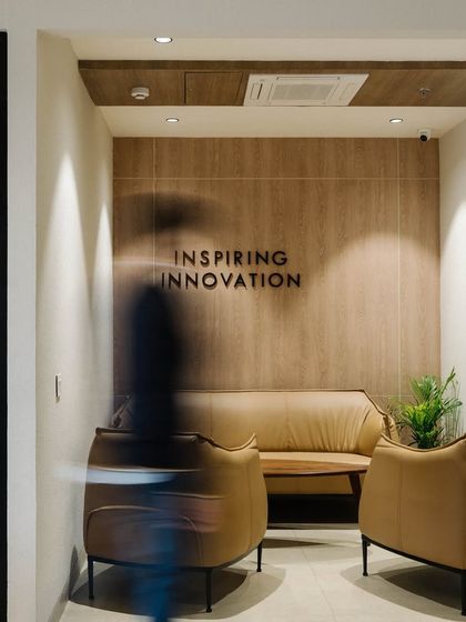 The "Inspiring Innovation" tagline is integrated into the wall of a waiting area, reinforcing the company's mission. The motion blur in the photo suggests the dynamic and active environment.