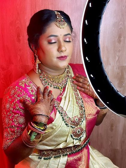 Getting ready for the big day. Our bride Nayana looks beautiful in a layered temple jewellery set with Kemp stones, perfectly matching her cream and pink saree.