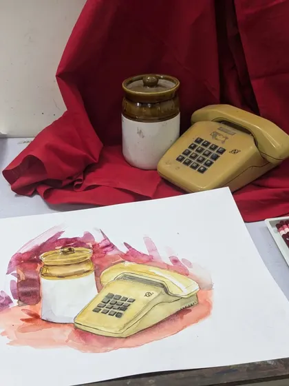 The setup for a still life painting. The student's artwork is placed next to the actual objects, showing the translation from 3D to 2D.