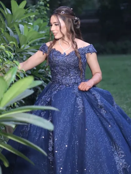 A candid shot capturing the elegance of the bride-to-be in her stunning blue gown and perfectly styled hair.