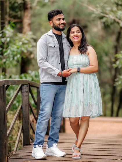 A happy couple enjoys a walk on a wooden bridge in a park, a simple and sweet moment from their pre-wedding session.