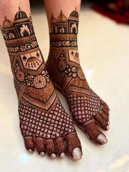 A stunning example of architectural motifs used in feet mehndi. The design features domes and archways, complemented by a full-coverage net pattern on the toes and foot.