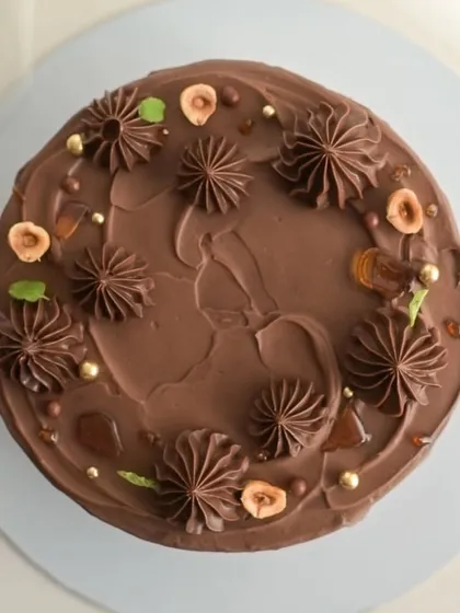 An overhead view of my Hazelnut Praline cake, showing the rustic yet elegant finish. I decorate it with piped chocolate ganache, toasted hazelnuts, and golden sugar pearls for a beautiful presentation.