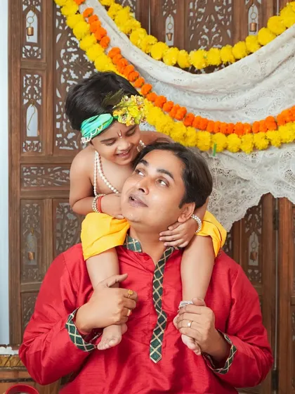 A father's joy, lifting his little Krishna onto his shoulders during a Janmashtami mini session. A playful and heartwarming moment.