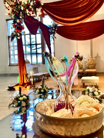 A close-up of the decorative details along the aisle, with colorful wands in a vase, set against the backdrop of the beautifully draped mandap.