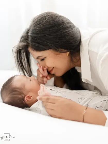 A mother and her newborn baby sharing a moment of connection. The soft, bright lighting creates a pure and angelic feel, perfect for newborn portraits.