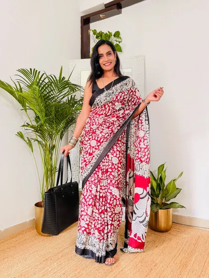 A red and white Kalamkari print saree, styled with a black blouse and tote bag for a smart, casual look. This is a perfect example of an everyday, stylish outfit.