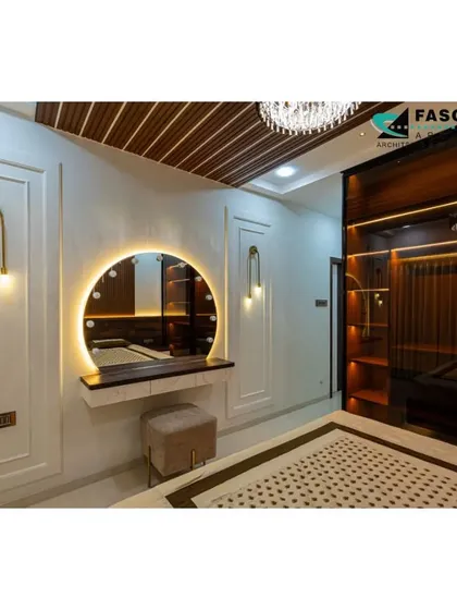 A glamorous bedroom featuring a large, round vanity mirror with studio lighting, perfect for getting ready. The design includes elegant wall paneling, artistic light fixtures, and a dark wood wardrobe with internal lighting.