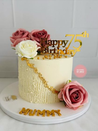 A beautiful and elegant cake for a 75th birthday. The textured buttercream, gold leaf detailing, and fresh roses create a sophisticated look.
